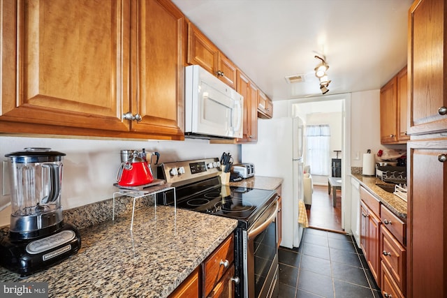 kitchen with stainless steel range with electric stovetop, dark tile patterned flooring, and dark stone countertops