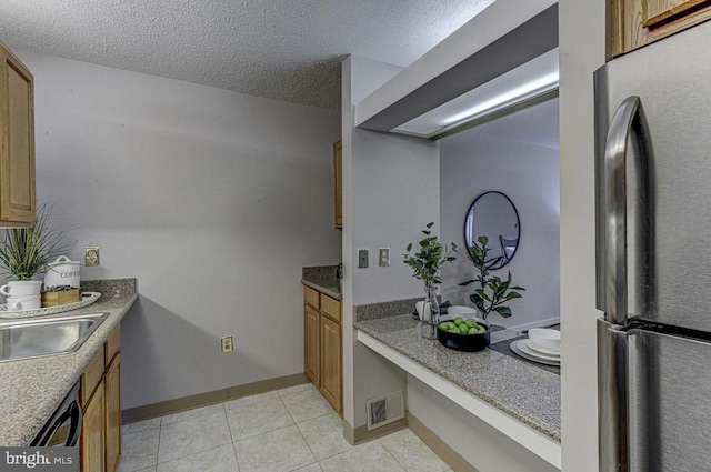 kitchen featuring black dishwasher, light tile patterned floors, stainless steel fridge, and a textured ceiling