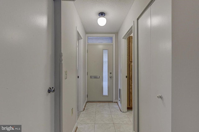 hall with light tile patterned floors and a textured ceiling