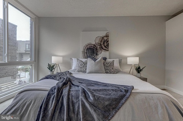 bedroom featuring multiple windows, a textured ceiling, and carpet flooring