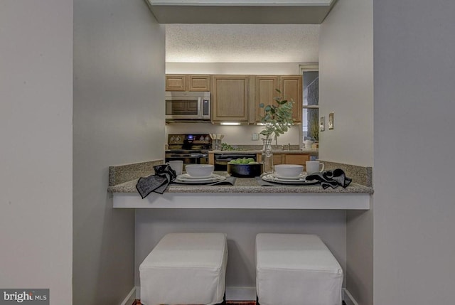 kitchen with electric stove, a kitchen breakfast bar, a textured ceiling, and light brown cabinets