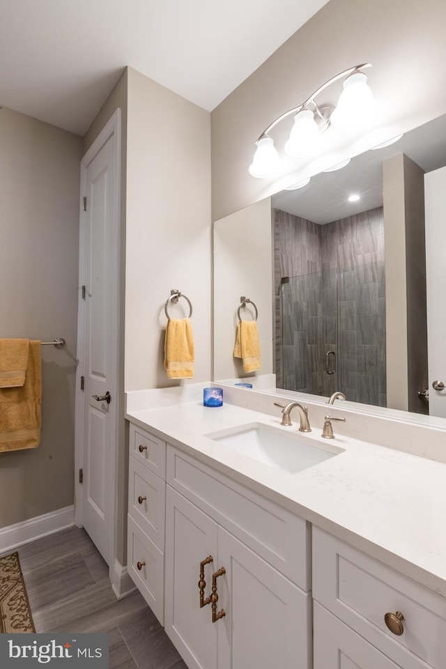 bathroom with hardwood / wood-style floors, vanity, and a shower with shower door