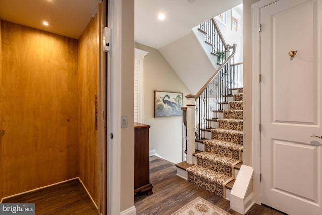 staircase with hardwood / wood-style flooring, lofted ceiling, and elevator