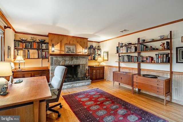 office featuring crown molding, light hardwood / wood-style flooring, and a stone fireplace