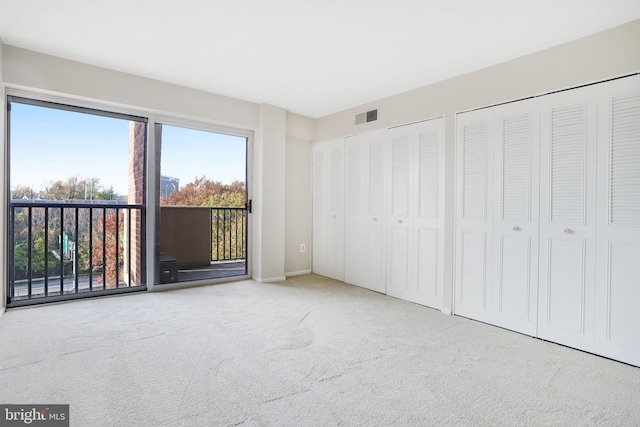 unfurnished bedroom featuring multiple closets, access to exterior, and carpet flooring