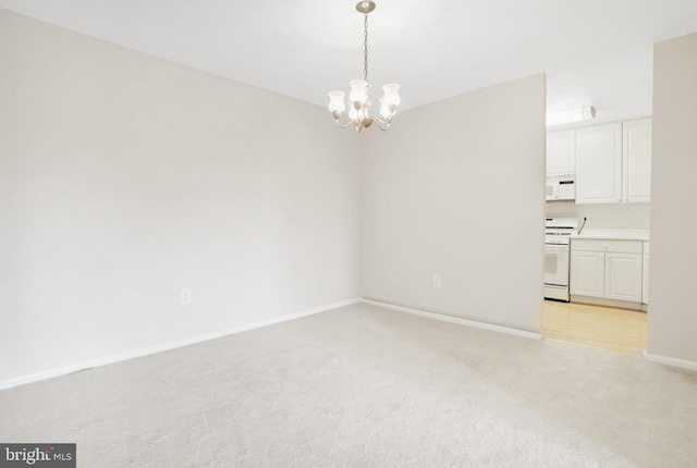 carpeted empty room with a notable chandelier