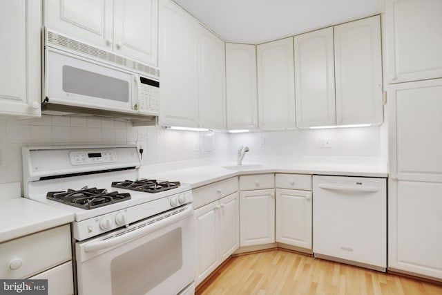 kitchen with light wood-type flooring, backsplash, white appliances, sink, and white cabinets