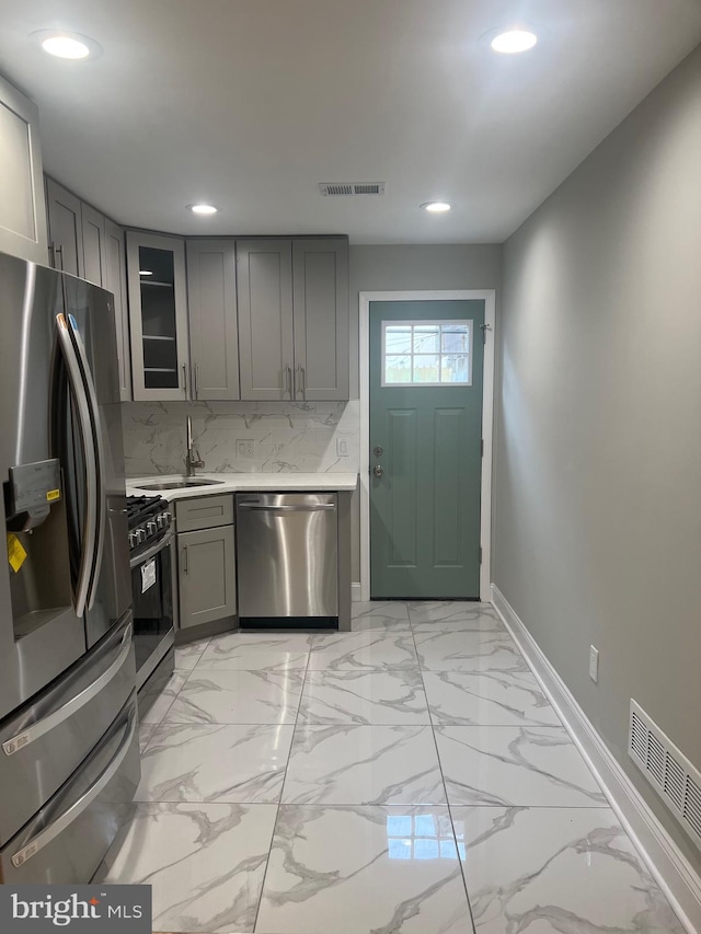 kitchen with gray cabinetry, stainless steel appliances, and tasteful backsplash