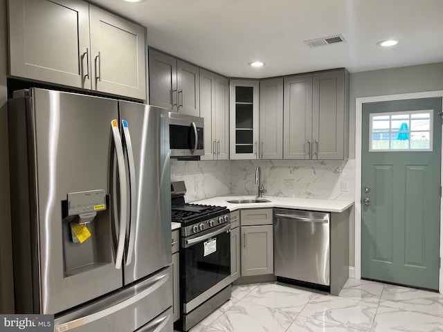 kitchen with appliances with stainless steel finishes, tasteful backsplash, sink, and gray cabinetry