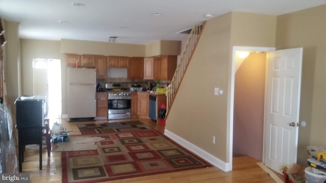 kitchen with stainless steel range oven, white fridge, and light wood-type flooring