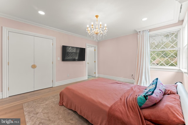 bedroom featuring light hardwood / wood-style floors, a closet, crown molding, and a notable chandelier