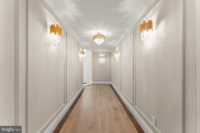 hallway with light wood-type flooring and crown molding