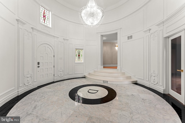 entryway with ornamental molding, dark hardwood / wood-style floors, an inviting chandelier, a high ceiling, and decorative columns