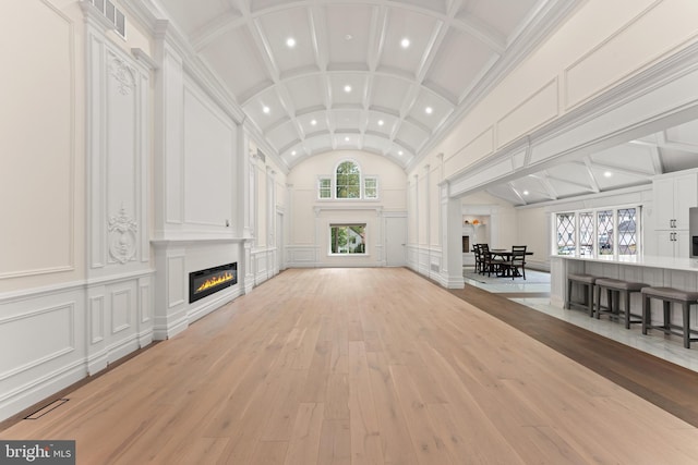 unfurnished living room with light hardwood / wood-style floors, a healthy amount of sunlight, a large fireplace, and vaulted ceiling