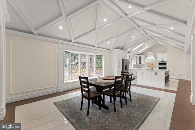 dining area featuring vaulted ceiling with beams and light hardwood / wood-style flooring