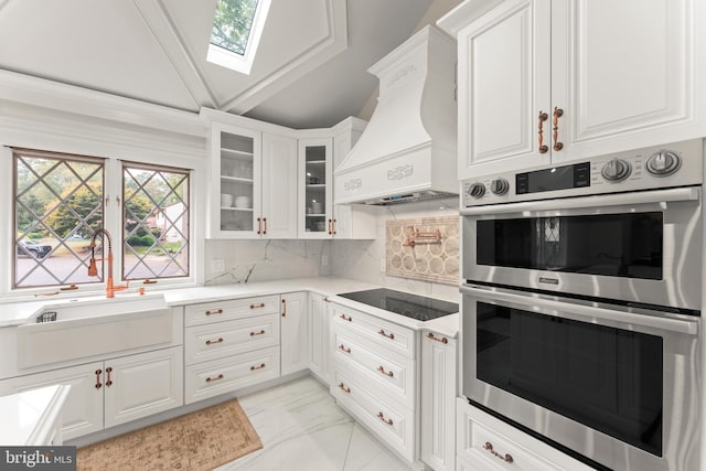 kitchen with white cabinets, black electric stovetop, premium range hood, and double oven