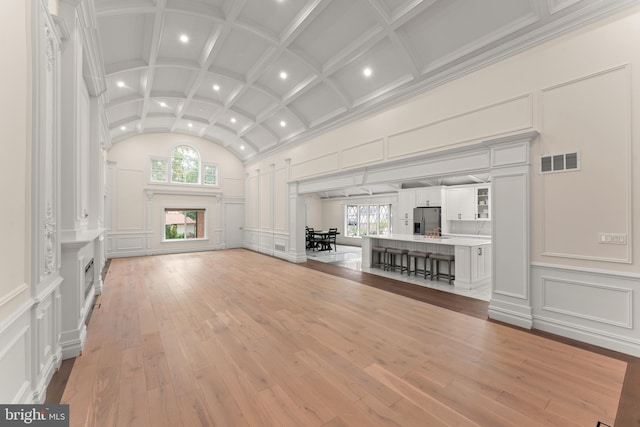 unfurnished living room featuring light hardwood / wood-style floors, a healthy amount of sunlight, and crown molding