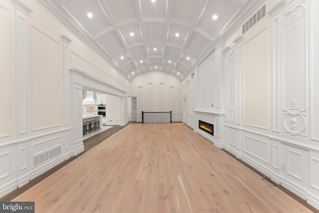 unfurnished living room with lofted ceiling, crown molding, and light hardwood / wood-style flooring