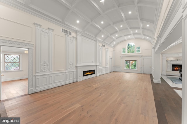 unfurnished living room with decorative columns, hardwood / wood-style floors, ornamental molding, and a towering ceiling