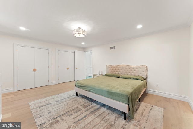 bedroom with ornamental molding, multiple closets, and light hardwood / wood-style flooring