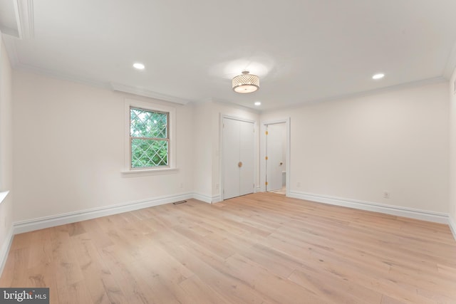 empty room featuring light hardwood / wood-style flooring and crown molding