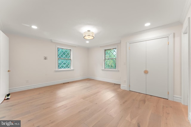 unfurnished bedroom with light hardwood / wood-style floors, multiple windows, crown molding, and a closet