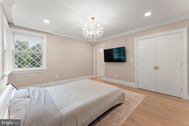 bedroom featuring light hardwood / wood-style floors, a chandelier, a closet, and ornamental molding