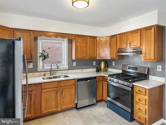 kitchen featuring light stone counters, stainless steel appliances, and sink