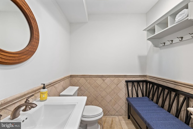 bathroom with toilet, tile walls, and sink