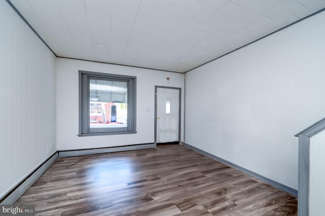 spare room with dark hardwood / wood-style floors, wooden walls, and a baseboard heating unit