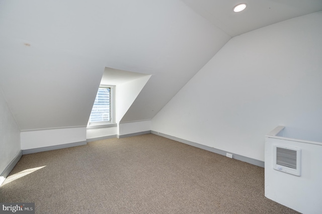 additional living space with heating unit, carpet floors, and vaulted ceiling