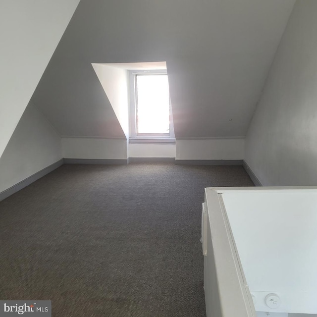 bonus room featuring dark colored carpet and vaulted ceiling