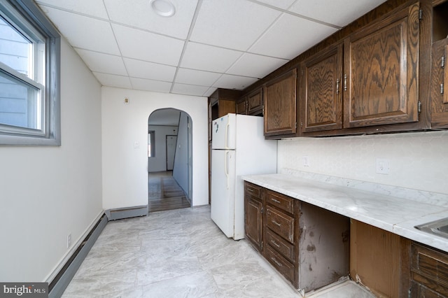 kitchen featuring dark brown cabinetry, white fridge, a paneled ceiling, and backsplash