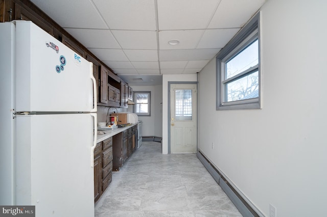 kitchen featuring dark brown cabinets, a paneled ceiling, white fridge, and plenty of natural light