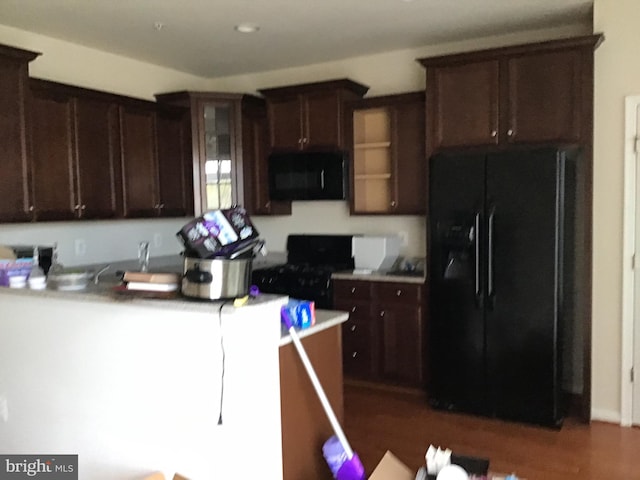 kitchen with black appliances and dark hardwood / wood-style flooring