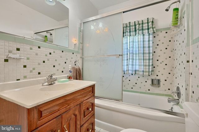 full bathroom with tile walls, vanity, bath / shower combo with glass door, and toilet