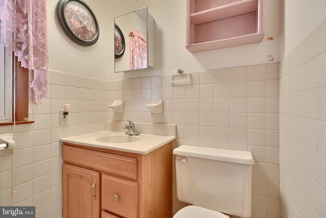 bathroom featuring vanity, toilet, and tile walls