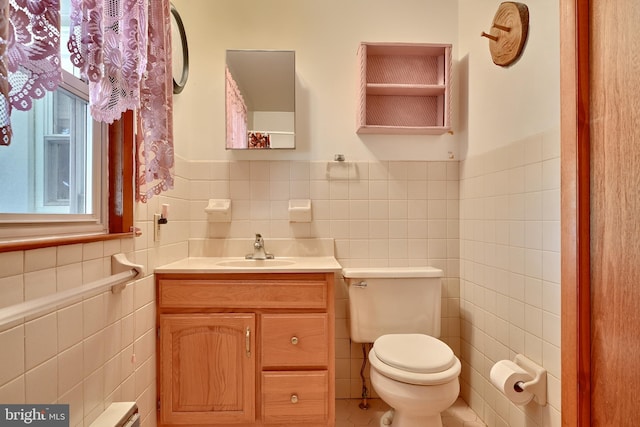 bathroom featuring toilet, vanity, tile patterned floors, and tile walls