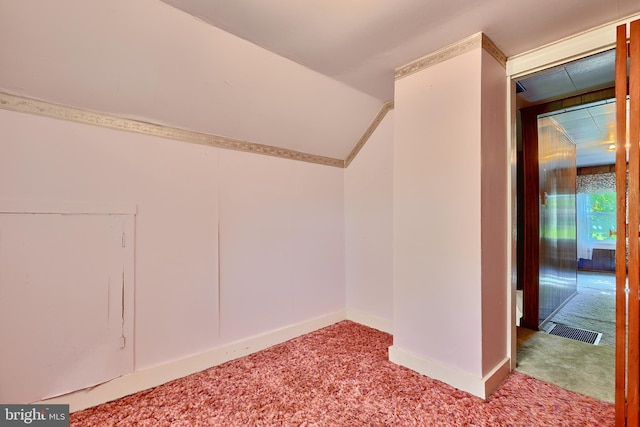 additional living space featuring vaulted ceiling and light colored carpet