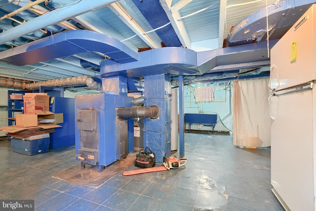 basement with sink, heating unit, and white refrigerator