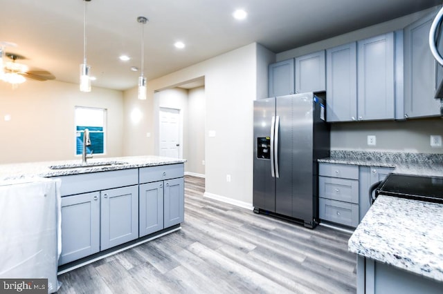 kitchen with stainless steel refrigerator with ice dispenser, gray cabinetry, ceiling fan, sink, and hanging light fixtures