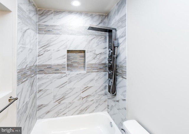 bathroom featuring toilet and tiled shower / bath