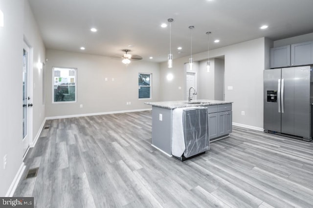 kitchen featuring ceiling fan, light stone counters, stainless steel refrigerator with ice dispenser, pendant lighting, and gray cabinets