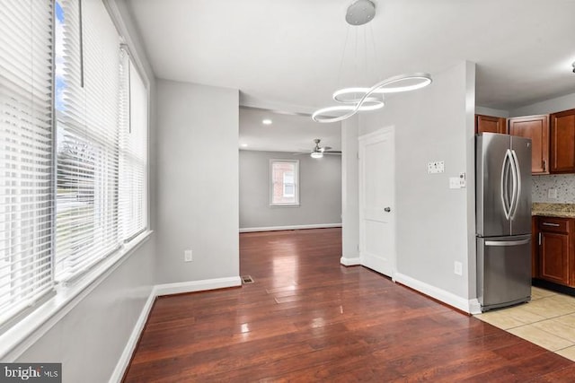 kitchen with tasteful backsplash, wood-type flooring, and stainless steel refrigerator