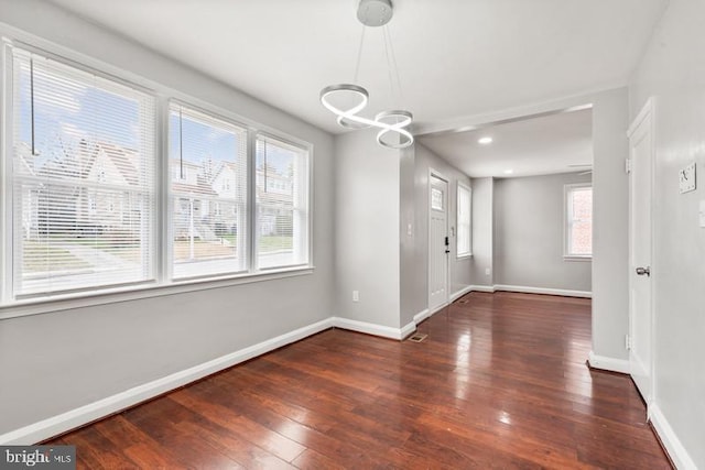 unfurnished dining area featuring a notable chandelier and dark hardwood / wood-style floors