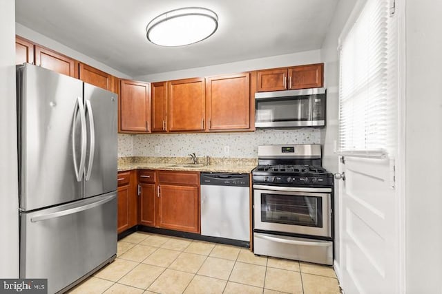 kitchen with light stone counters, stainless steel appliances, sink, and light tile patterned floors