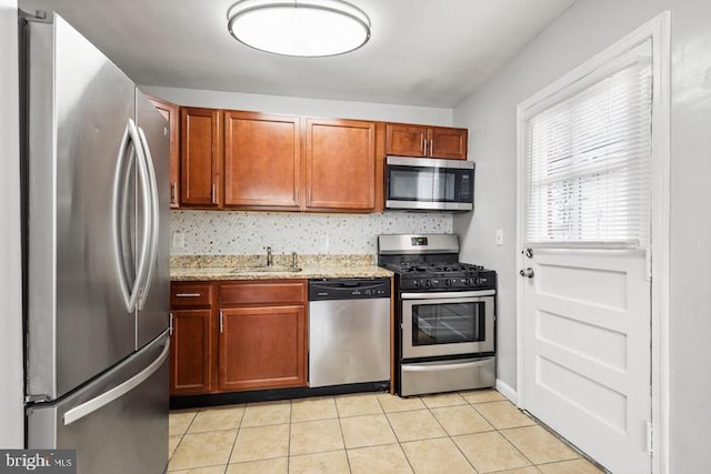 kitchen featuring light stone countertops, appliances with stainless steel finishes, sink, and light tile patterned floors