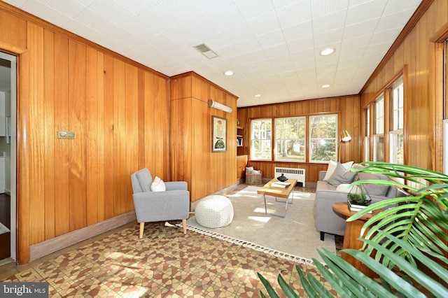 living room with wood walls, ornamental molding, and radiator heating unit