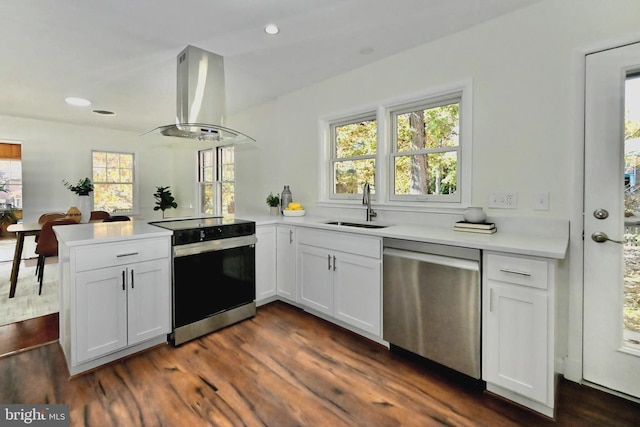 kitchen featuring appliances with stainless steel finishes, sink, island range hood, kitchen peninsula, and white cabinets