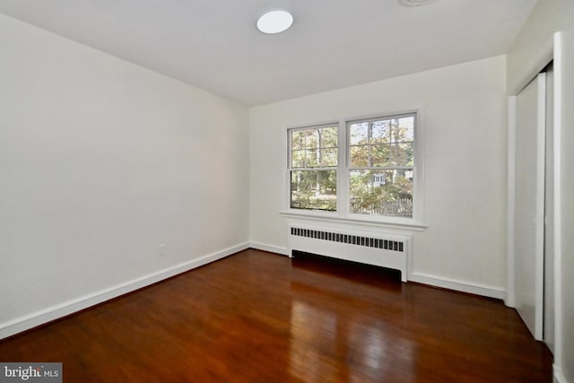 empty room with radiator and dark wood-type flooring